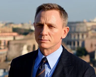 Daniel Craig as James Bond in a suit with a cityscape background.