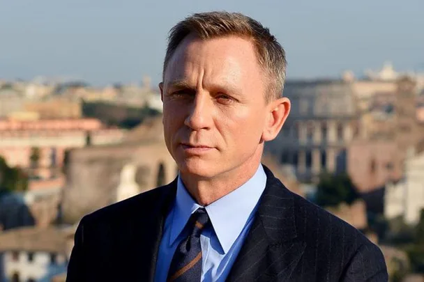 Daniel Craig as James Bond in a suit with a cityscape background.