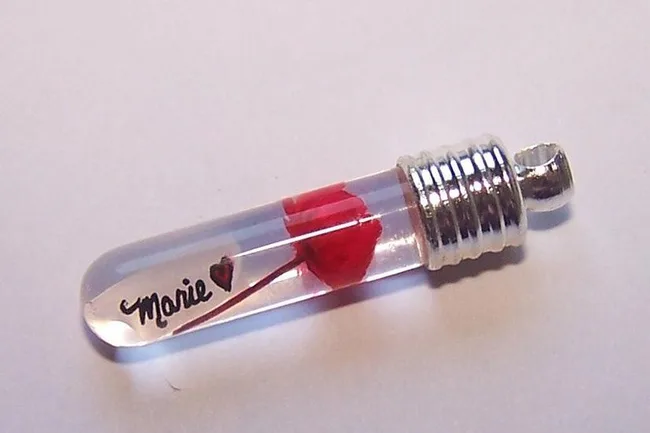 Glass vial pendant with a tiny red rose and the name "Marie" written inside.