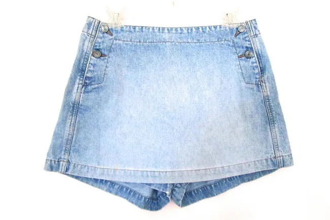 Denim skirt with side buttons and faint pleats on a white background.