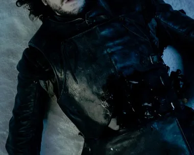 Jon Snow, wounded and lying on snow in dark armor, from "Game of Thrones."