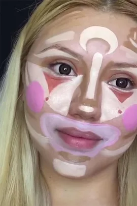 Person with blonde hair, face covered in various colors of contouring makeup for cosmetic styling demonstration.