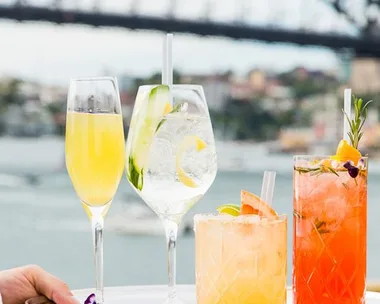 Four elegant summer cocktails on a tray with the Sydney Harbour Bridge in the background.