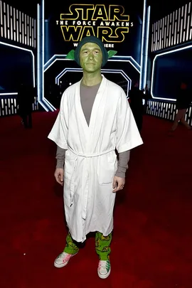 Person dressed as Yoda in white robe and green face paint at "Star Wars: The Force Awakens" premiere.