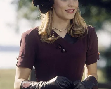 Rachel McAdams as Allie Hamilton in "The Notebook" wearing a vintage maroon dress, gloves, and hat, smiling outdoors.