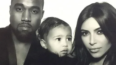 Black-and-white photo featuring two adults and a child between them, all looking towards the camera with neutral expressions.