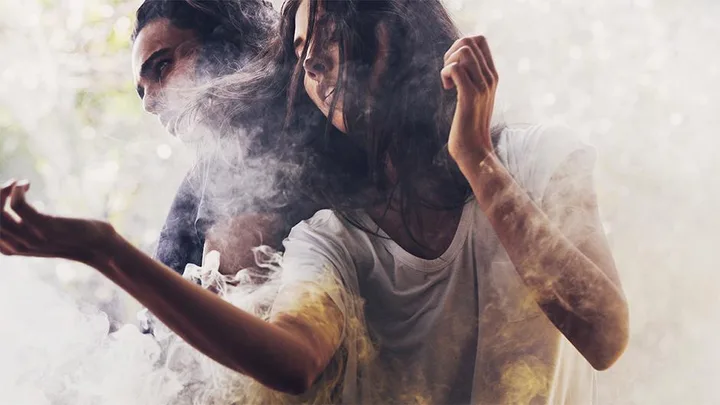 Two models in casual T-shirts surrounded by smoke in an ethereal, dreamy setting.