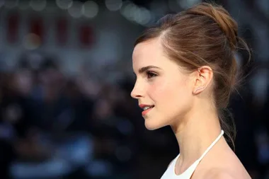 Actress Emma Watson at a public event, wearing an elegant updo and white halter dress.