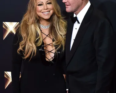 Mariah Carey and James Packer smiling at a formal event, Carey in a black dress, Packer in a black suit.