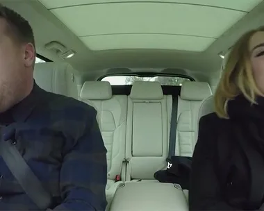 James Corden and Adele laughing together while filming "Carpool Karaoke" segment inside a car.