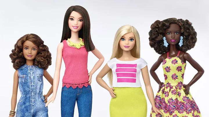 A group of four diverse Barbie dolls with different skin tones, hairstyles, and outfits, showcasing a historic makeover.