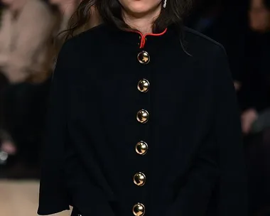 A model in a black coat at a Burberry show, holding hands up with "BO" on one palm and "WIE" on the other, paying tribute to David Bowie.