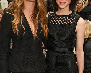 Cara Delevingne and another woman in black outfits at a fashion event.