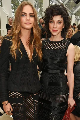 Cara Delevingne and another woman in black outfits at a fashion event.