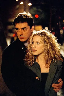 Carrie Bradshaw and Mr. Big embrace on a dimly lit street at night.