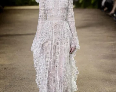 Model walks runway in intricate white lace gown with high neck and long sleeves at Elie Saab Haute Couture SS16 show.