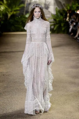 Model walks runway in intricate white lace gown with high neck and long sleeves at Elie Saab Haute Couture SS16 show.