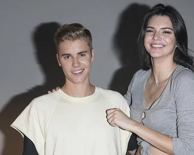 Justin Bieber stands with a smiling woman in a gray top.