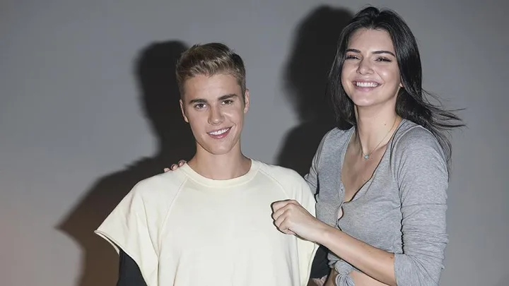 Justin Bieber stands with a smiling woman in a gray top.