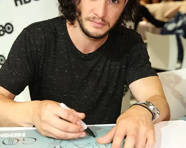 Actor signing a Game of Thrones poster at an HBO event.