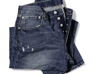 A pair of blue jeans with a small front pocket, commonly known as a coin pocket, on a white background.