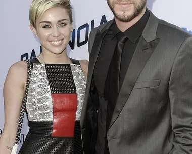 Miley Cyrus and Liam Hemsworth pose together on the red carpet at the Paranoia premiere.