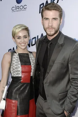 Miley Cyrus and Liam Hemsworth pose together on the red carpet at the Paranoia premiere.