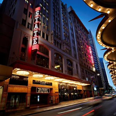 "Nighttime view of the State Theatre in Sydney, with illuminated signs and lights on George Street."