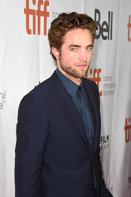 A man in a navy blue suit at the Toronto International Film Festival, standing in front of a backdrop with TIFF and Bell logos.