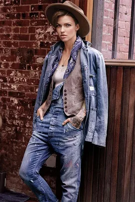A model in a denim outfit and hat poses against a rustic brick wall in a Ralph Lauren campaign.