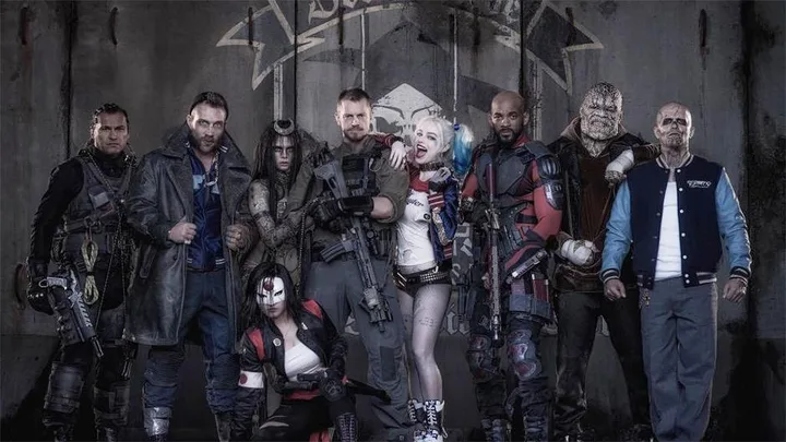 The Suicide Squad characters in costume, including Harley Quinn, Deadshot, Rick Flag, Captain Boomerang, and Katana, posing together.