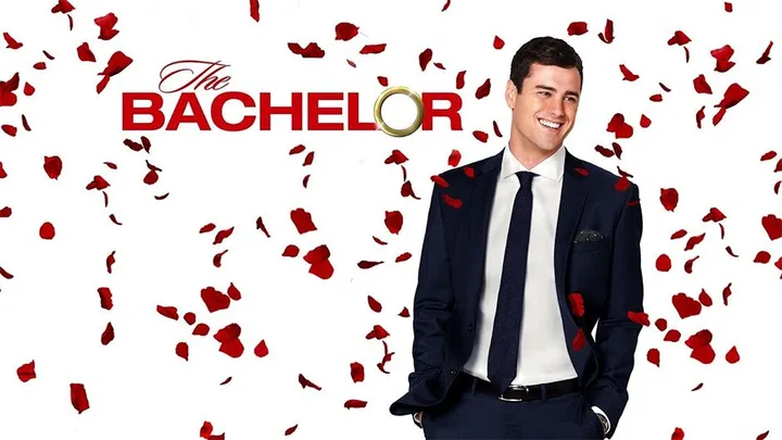 The Bachelor promotional image with a man in a suit surrounded by rose petals.