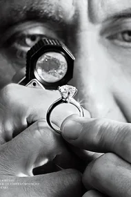 A gemologist examining a diamond ring with a loupe, celebrating 130 years of the Tiffany Setting.