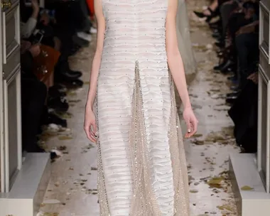 Model in a textured white and silver Valentino gown walks down a petal-strewn runway during the SS16 haute couture show.