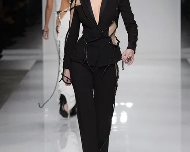 Model walks runway in a black, cutout Atelier Versace suit during haute couture Spring/Summer 2016 fashion show.