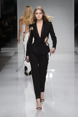 Model walks runway in a black, cutout Atelier Versace suit during haute couture Spring/Summer 2016 fashion show.