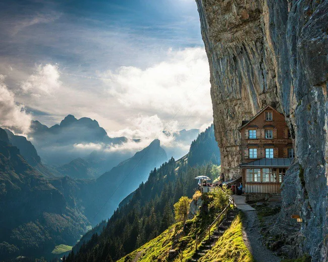 A mountain guesthouse built into a cliffside with scenic views, under a cloudy sky.