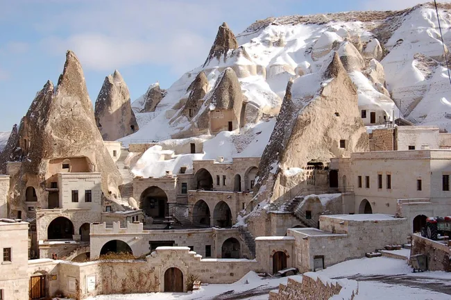 Cappadocia's snow-covered rock formations and ancient cave dwellings under a clear sky.