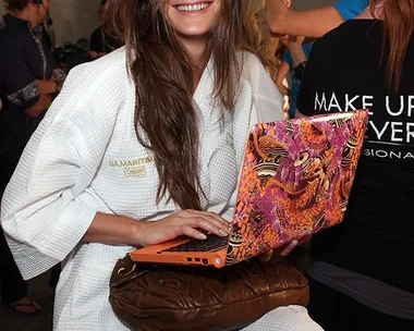 Model backstage holding a laptop computer.