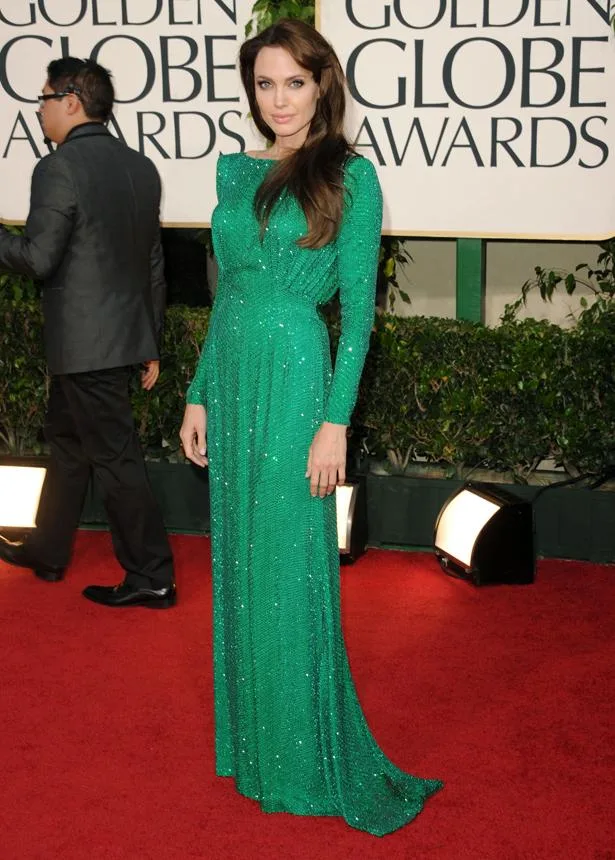 A person in a sparkling green gown poses on the red carpet at the Golden Globe Awards.