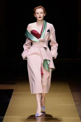 Model in Atelier Versace Fall 2016 couture, wearing an off-shoulder pink coat with green accents on runway.