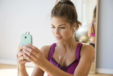 Woman in workout gear with iPhone headphones in.