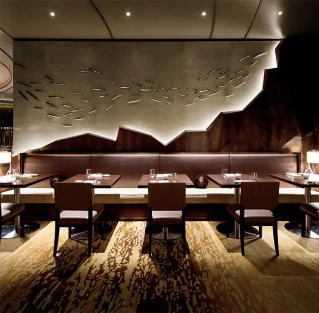 Elegant restaurant interior with modern decor, featuring tables, chairs, and artistic wall design with ambient lighting.