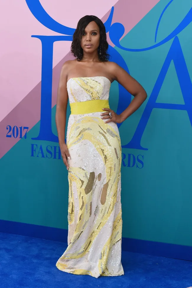 A person poses in a strapless yellow and white gown at the 2017 Fashion Awards.