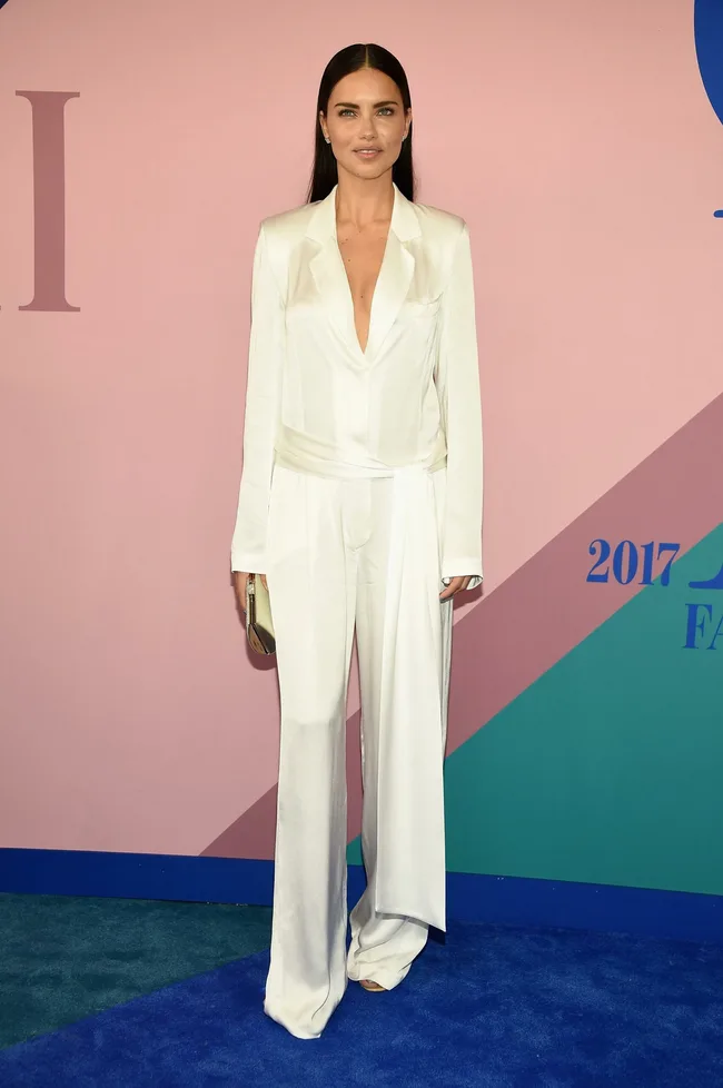 Woman in a white suit on a red carpet, standing in front of a colorful background featuring the year 2017.