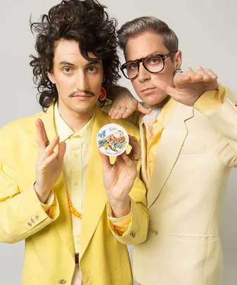 Two men in yellow suits holding a Kiehl's product, striking a pose with one looking directly at the camera.