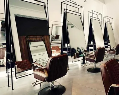 Contemporary hair salon interior with stylish mirrors and brown leather chairs lined up in a row.