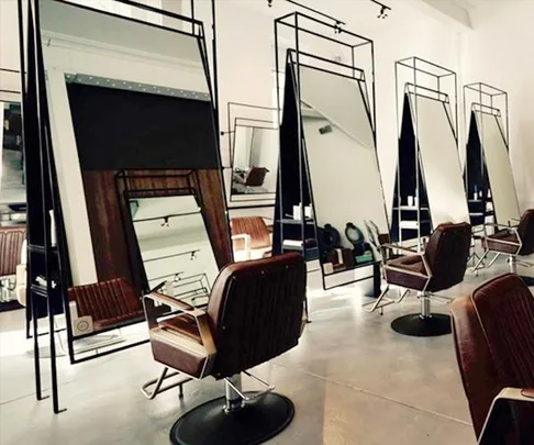 Contemporary hair salon interior with stylish mirrors and brown leather chairs lined up in a row.