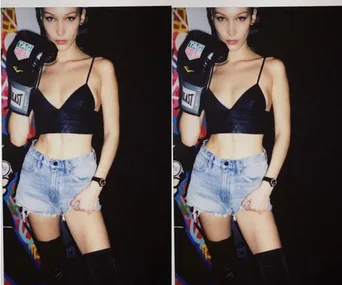 Bella Hadid posing in black crop top, denim shorts, and boxing gloves, standing in front of a colorful background.