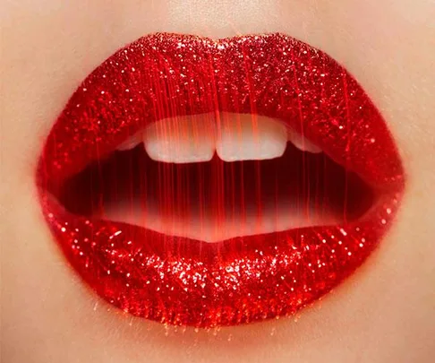 Close-up of glossy, glittery red lips slightly parted, showcasing a vibrant and bold makeup look.